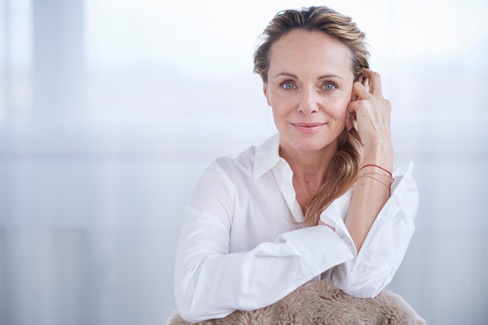 Jo Kern in weißer Bluse, mit der Hand an der Schläfe, vor einem hellen Hintergrund.